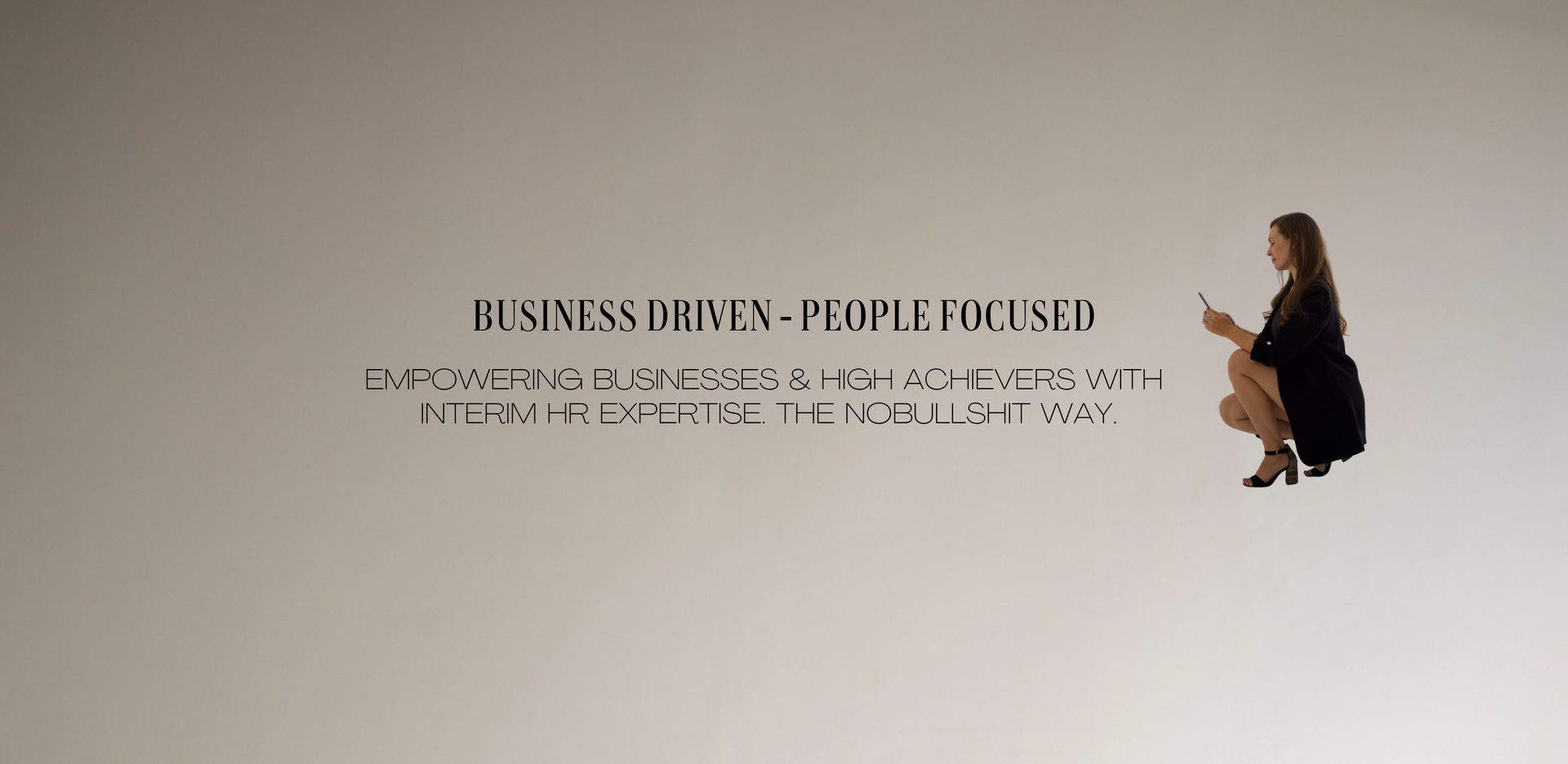 Business driven – people focused. Empowering businesses & high achievers with interim HR expertise. The no-bullshit way. Denise in Schwarz, hockend, mit Telefon in der Hand.